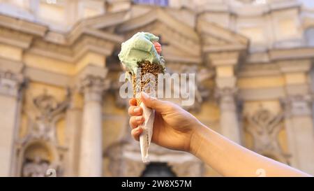 Italian dish - Italian Ice cream corn in hand - Italian Gelato in Woman`s Hand. Woman hand holding italian gelato ice cream cone Stock Photo